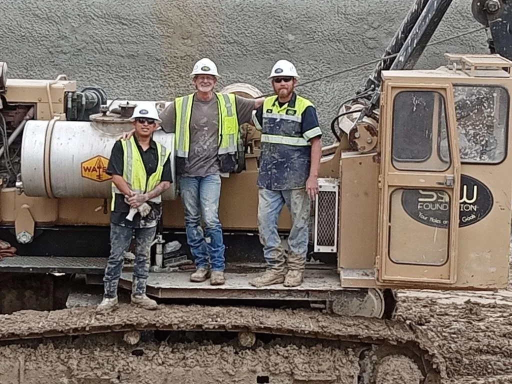 S&W Employees posing on their Pier Drilling Rig while perfoming foundation repair as a Foundation Contractors on a Commercial Construction Jobsite