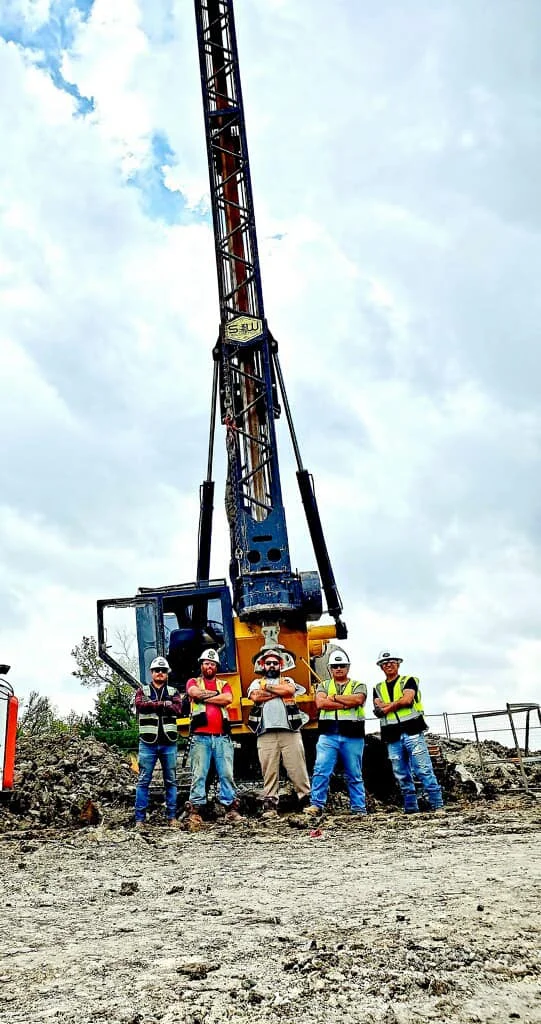 S&W Crew posing in front of the Pier Drilling Rig on a jobsite where they are working as Foundation Contractors